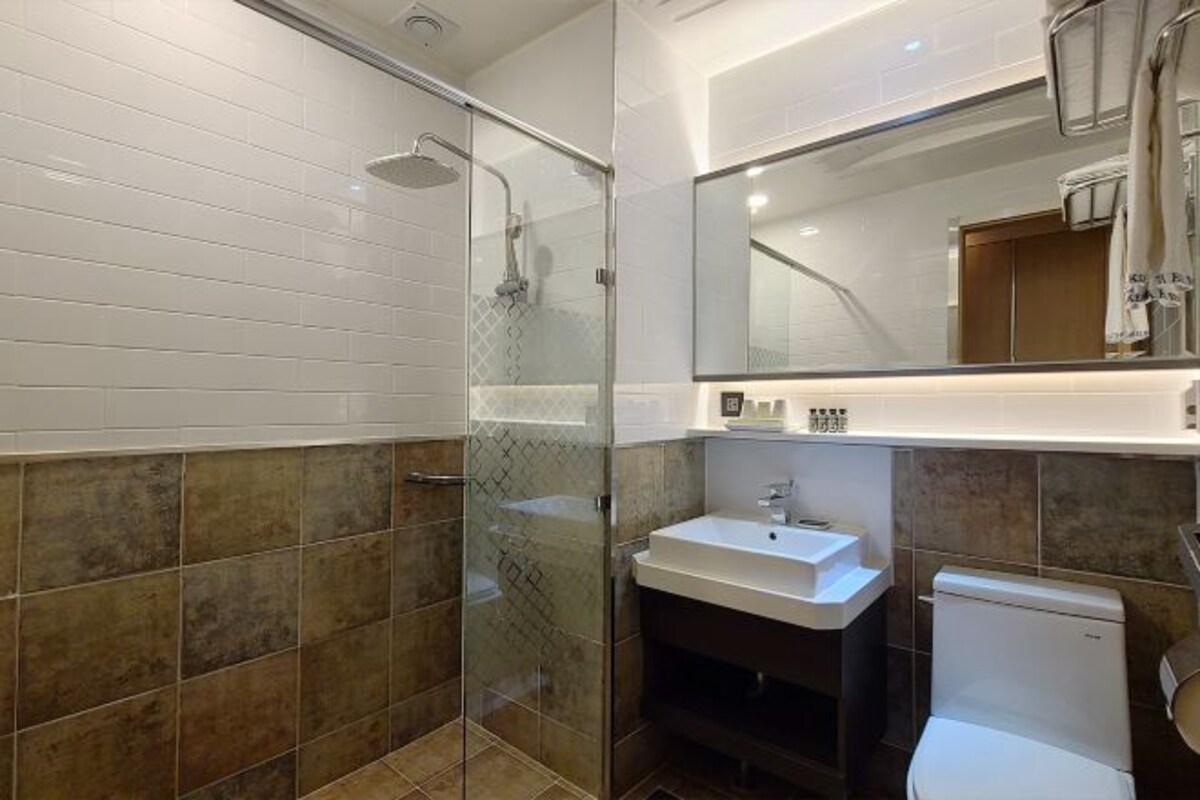 Une salle de bain moderne avec une douche à parois de verre, un lavabo blanc et des toilettes.