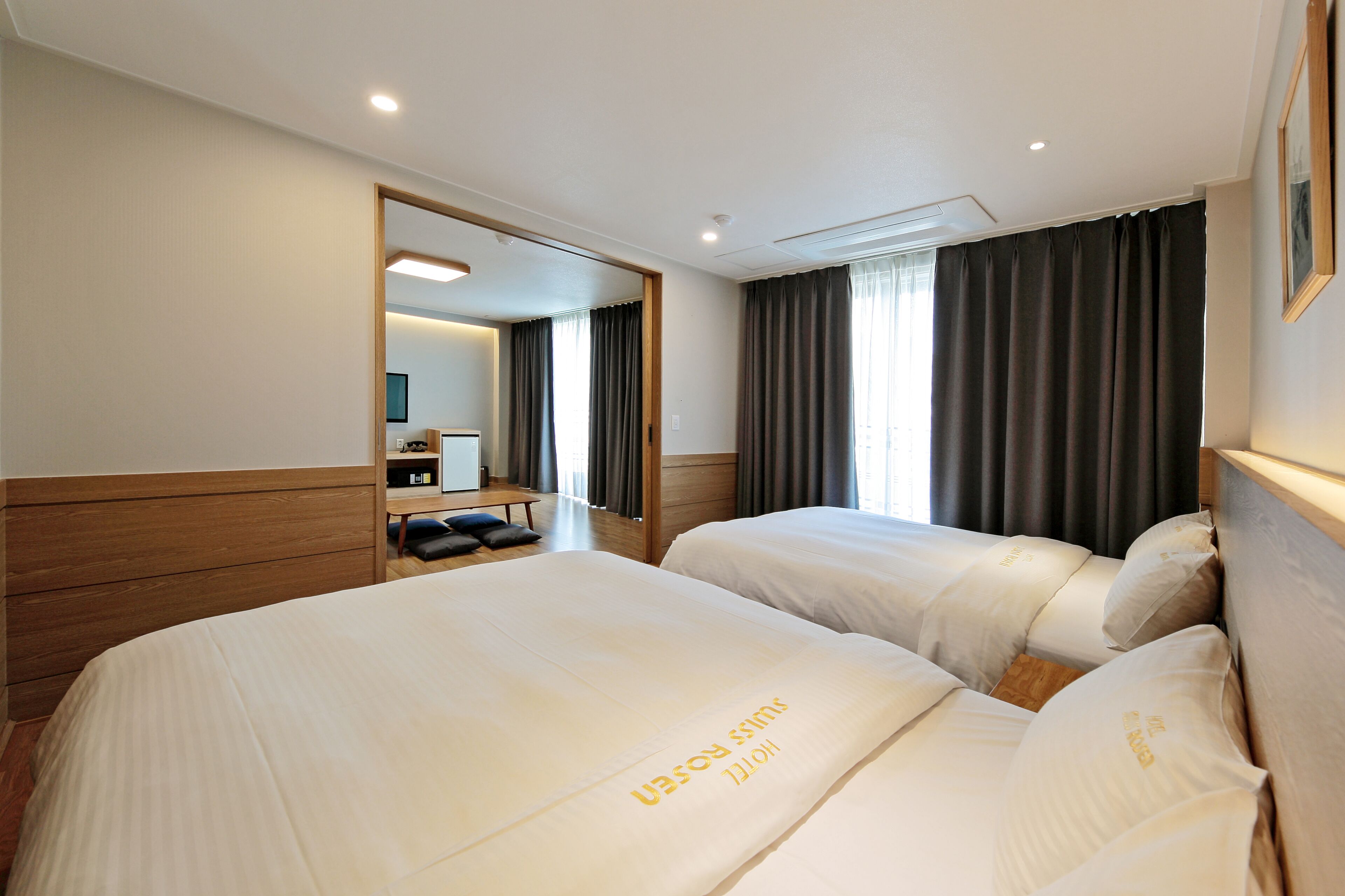A hotel room with two beds, a wooden headboard, a mirror, and a view of the hallway.