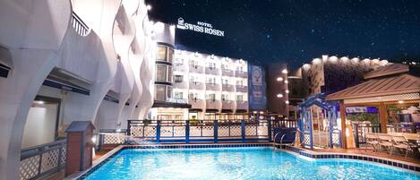 A swimming pool area with a hotel named 'Hotel Swiss Rosen' in the background.