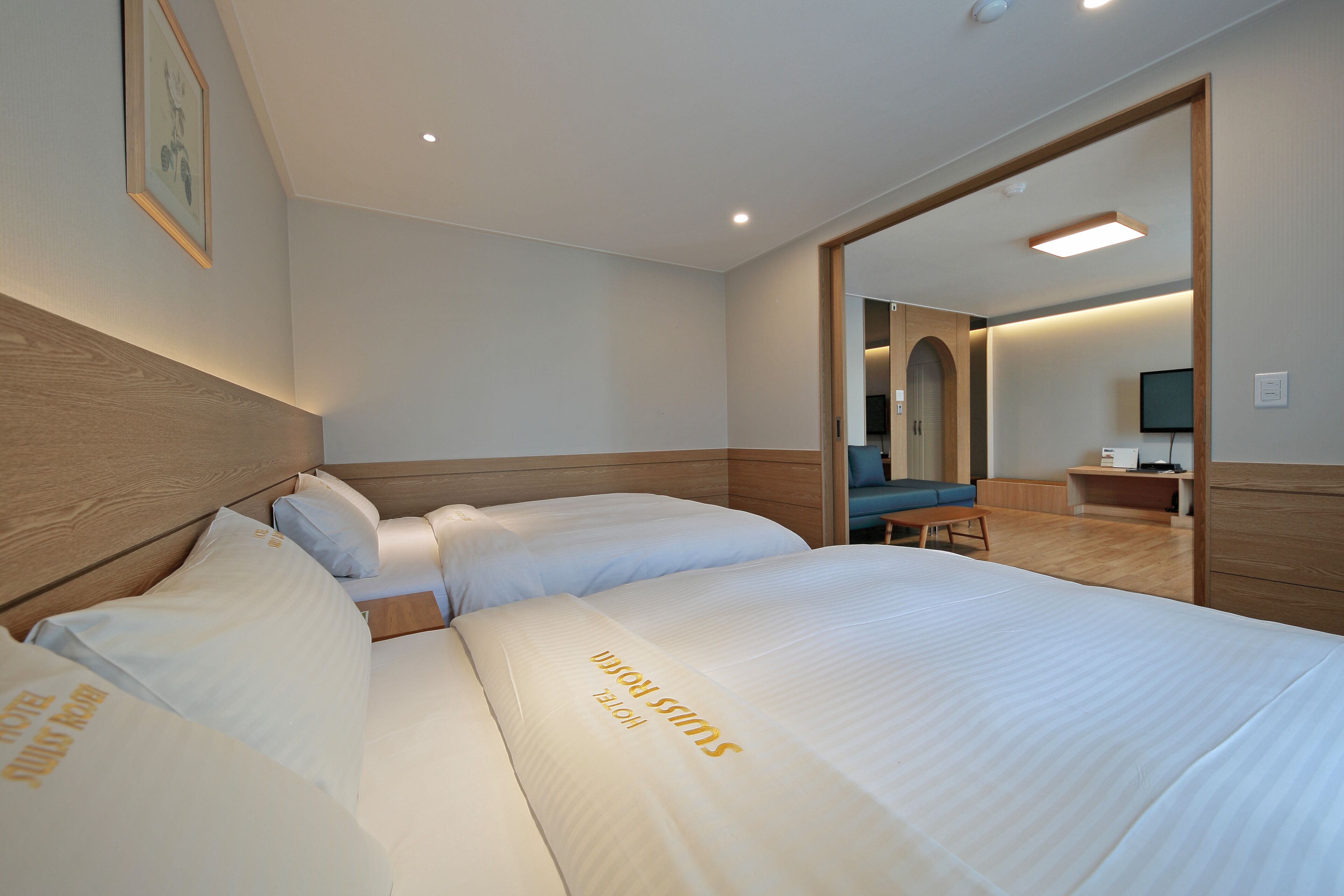 A hotel room with two beds, a wooden headboard, a mirror, a desk, and a television.