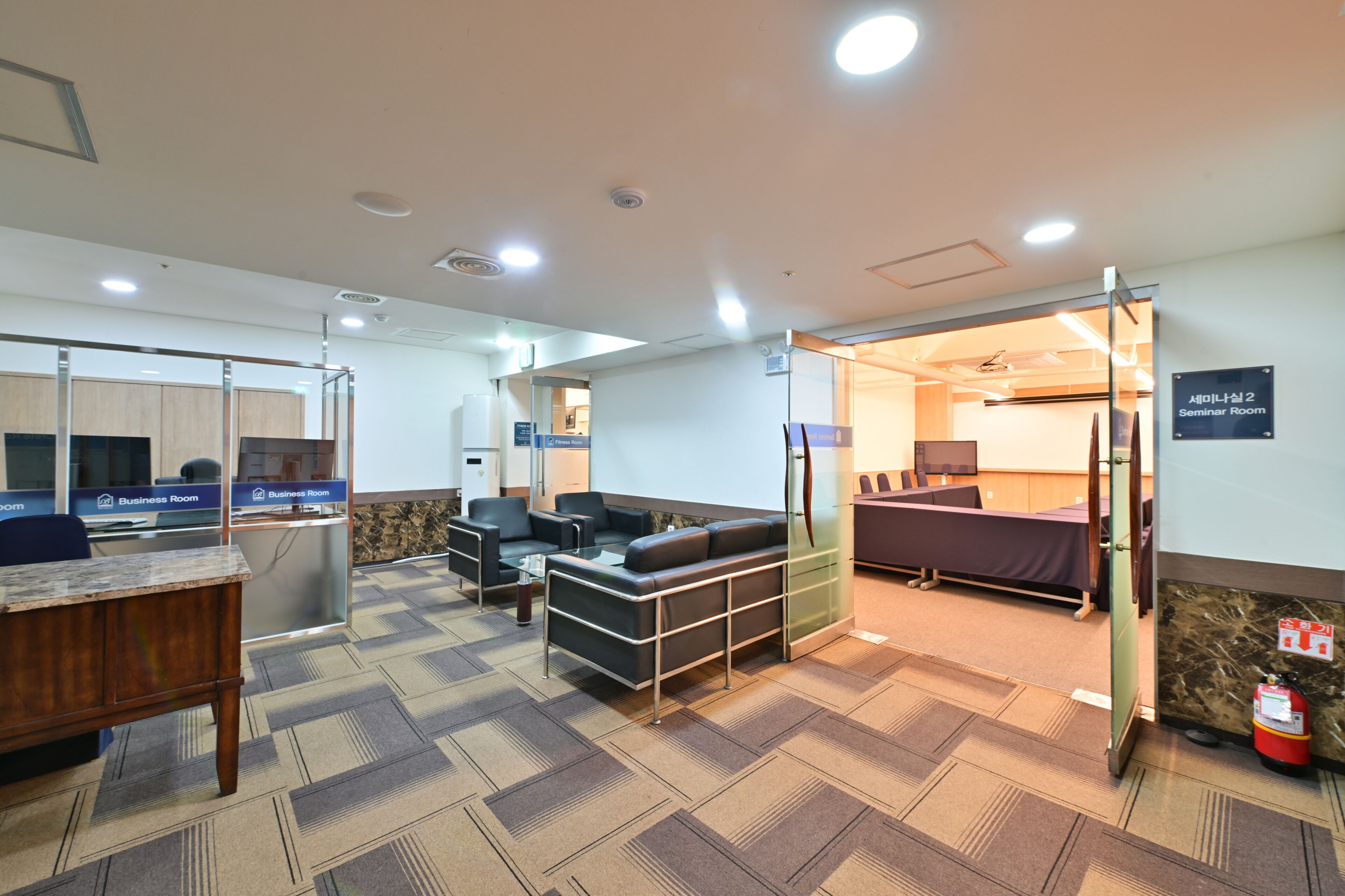 Una habitación de hotel para negocios con sofá, escritorio y cama.