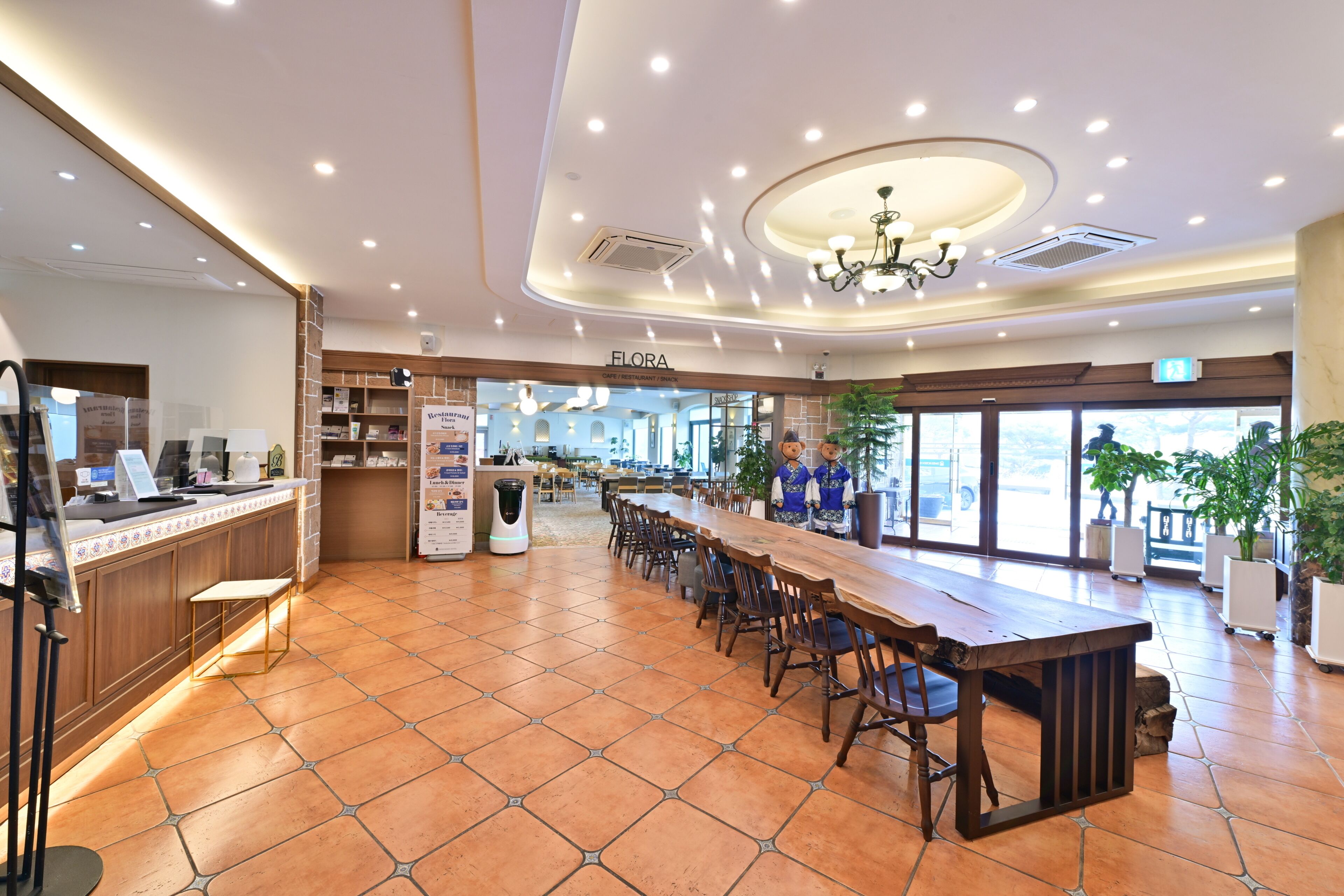Un'ampia sala da ristorante con un lungo bancone, numerosi posti a sedere e un soffitto alto con illuminazione a incasso.