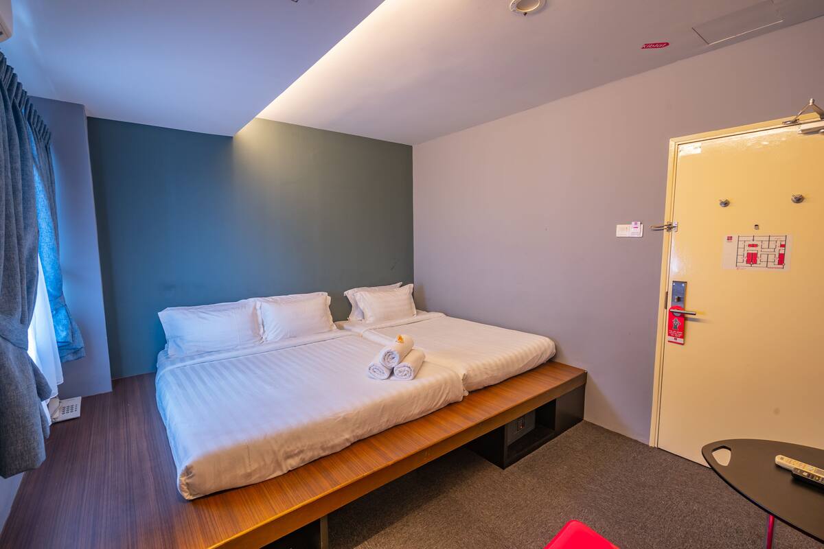 A hotel room with a bed, bedside table, and a wardrobe.
