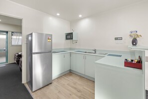 A modern kitchen with a refrigerator, microwave, and sink. - Birchwood Spa Motel (Rotorua)