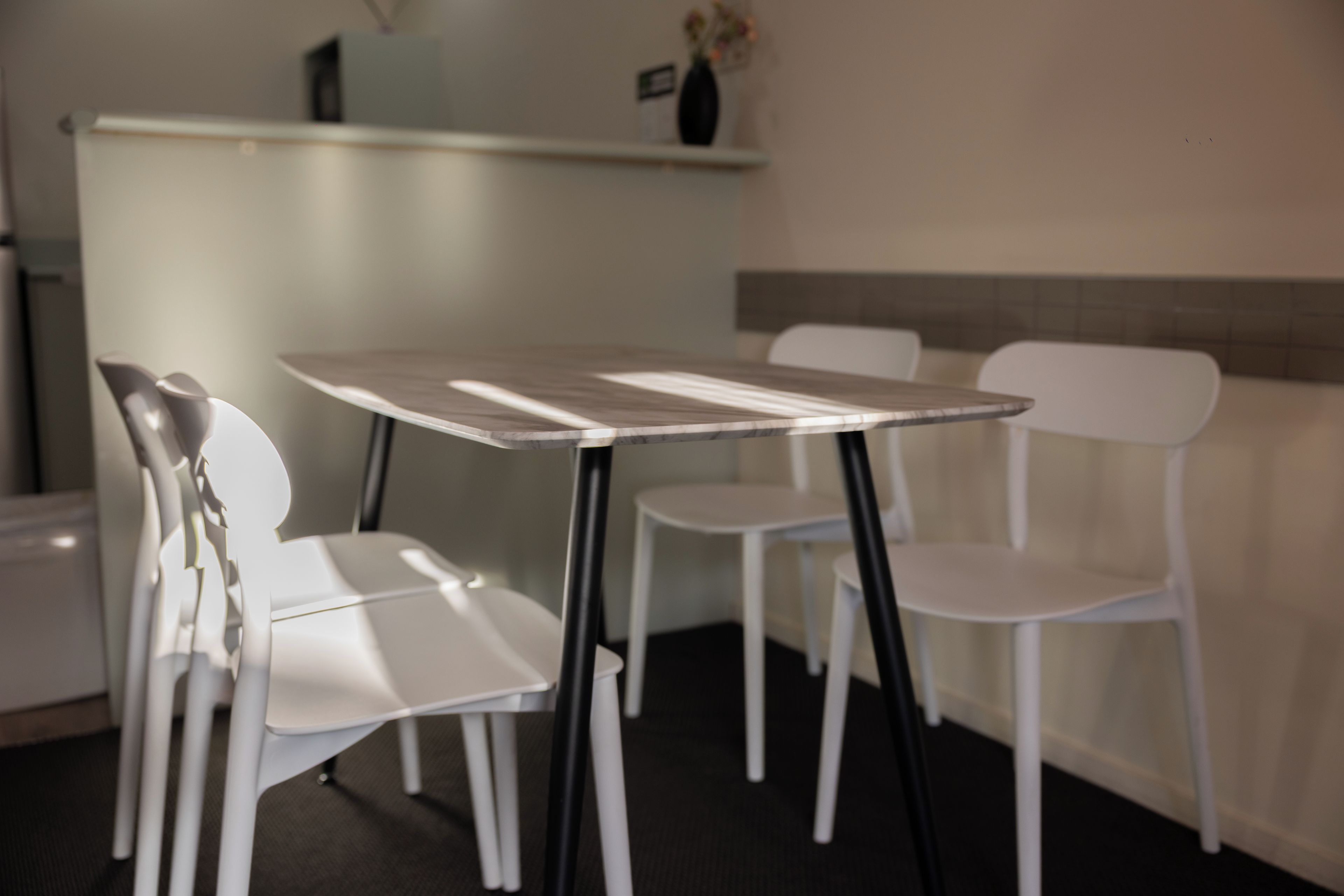 A small dining area with a square table and four white chairs.