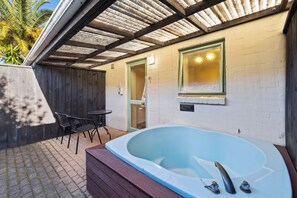 A spa area with a hot tub, a table, and chairs. - Birchwood Spa Motel (Rotorua)