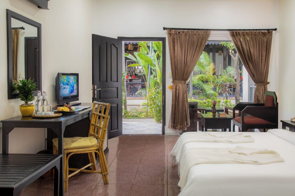 A hotel room with a bed, a desk with a computer, a chair, and a view of the outside.