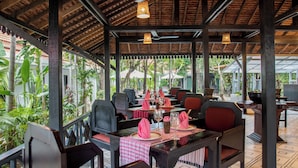 Un restaurant en plein air, avec des tables disposées pour accueillir les clients, entouré d’une végétation luxuriante.