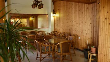 Un coin repas avec une table et des chaises en bois, une plante en pot et un miroir au mur.