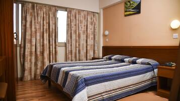 Una habitació d'hotel amb un llit, una tauleta de nit, una làmpada i un quadre a la paret.
