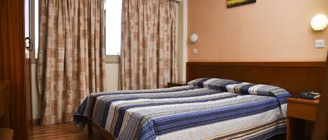 Quarto de hotel com uma cama, mesa de cabeceira, abajur e um quadro na parede.
