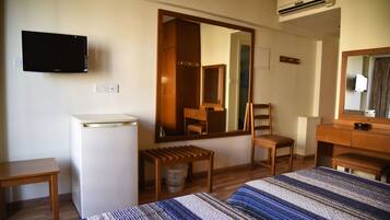 Une chambre d’hôtel équipée d’un lit, d’un bureau, d’une chaise, d’un miroir, d’une télévision et d’un appareil de climatisation.