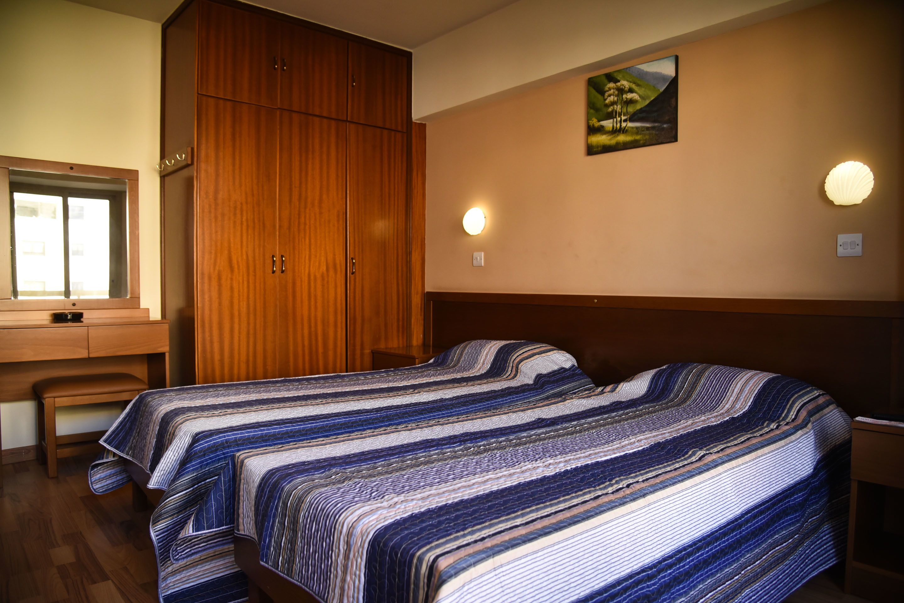 Un dormitorio con cama, armario de madera, escritorio y ventana.