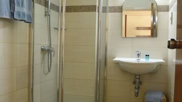 Un baño con ducha de vidrio, lavamanos y retrete.