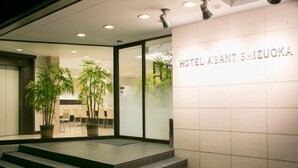 The entrance of Hotel A'Bout Shizuoka with a modern design, featuring a glass facade, potted plants, and a signboard. - Hotel Abant Shizuoka (Shizuoka)