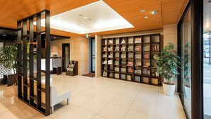A modern reception area with a wooden ceiling, a reception desk, a seating area, and a bookshelf with books. - Hotel Abant Shizuoka (Shizuoka)