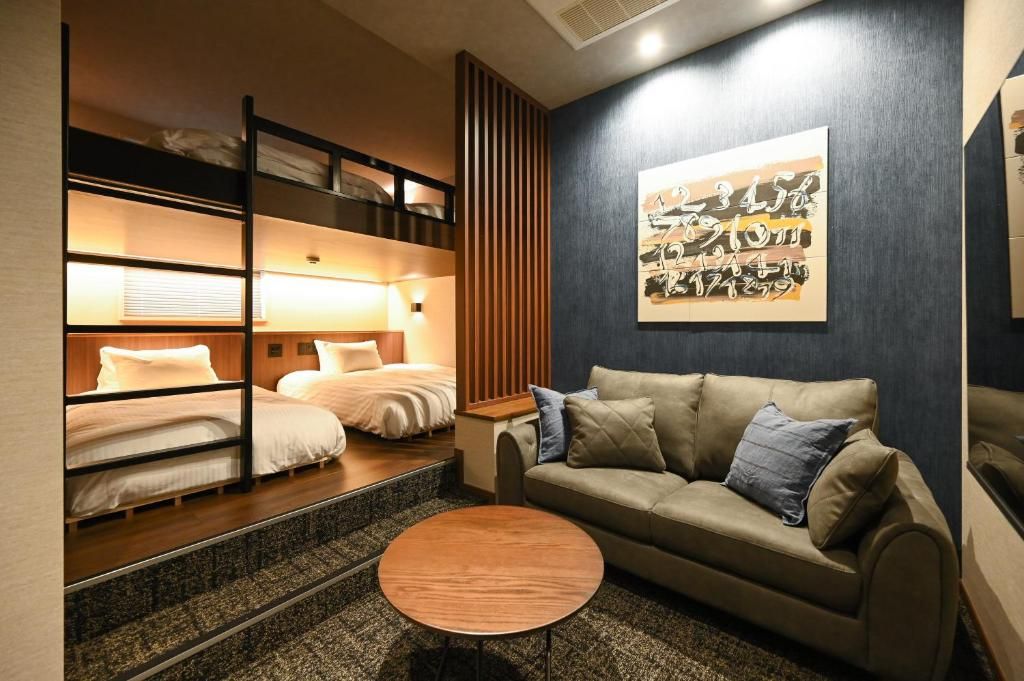 A hotel room with bunk beds, a sofa, a coffee table, and artwork on the wall.