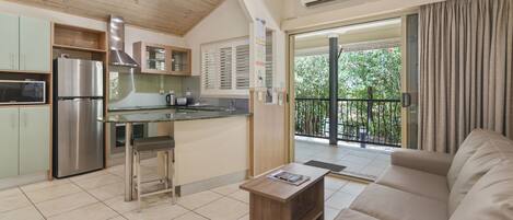 Una cocina moderna con un refrigerador de acero inoxidable, techo de madera y puerta corrediza de vidrio que da a un balcón.