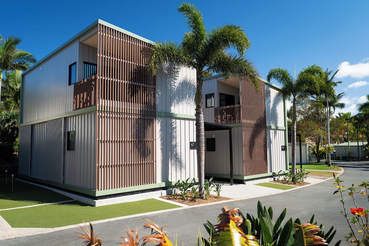 A modern two-story building with a flat roof, large windows, and a balcony.