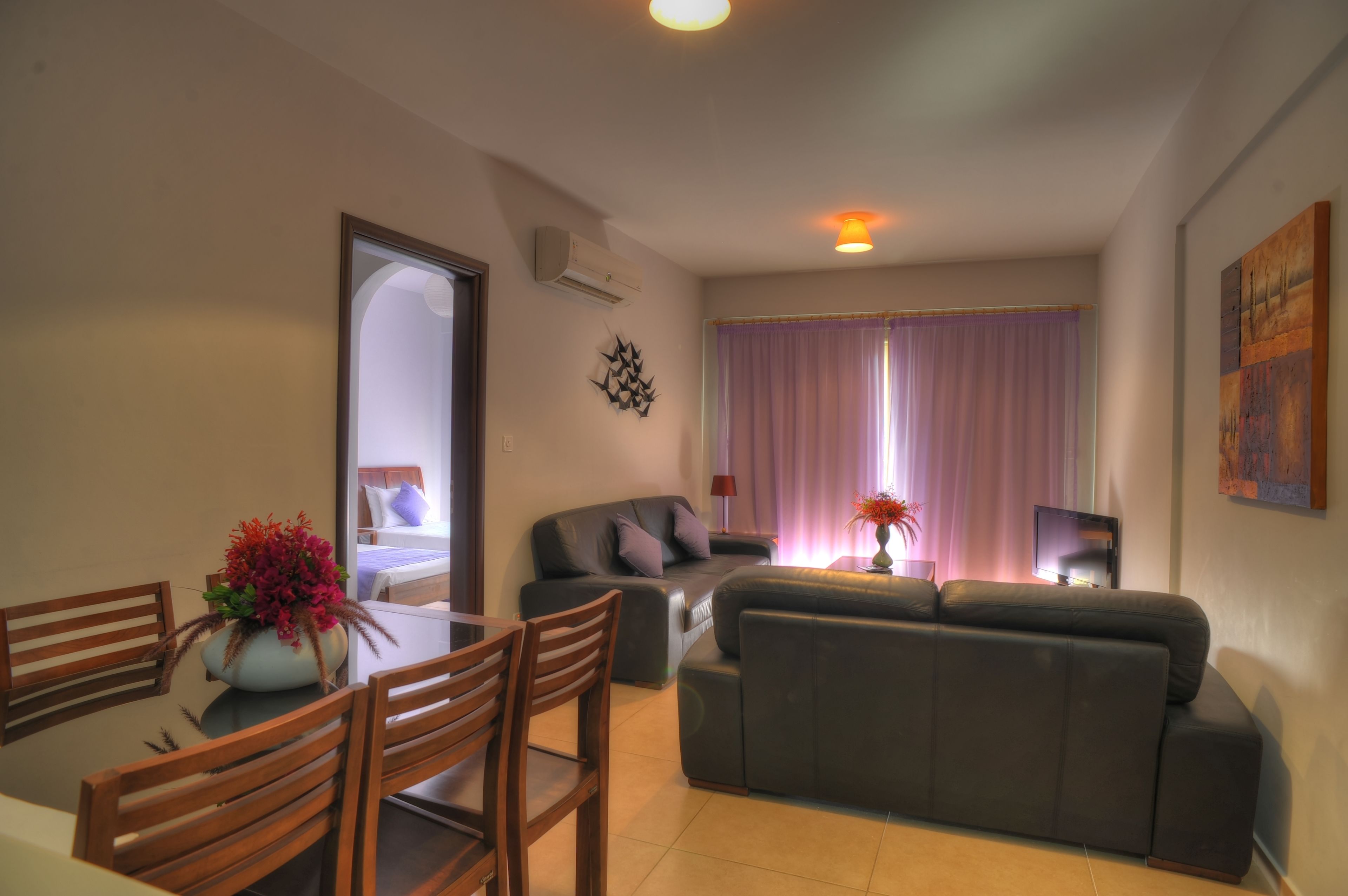 Una sala de estar con sofá, mesa de comedor y sillas, y televisor.