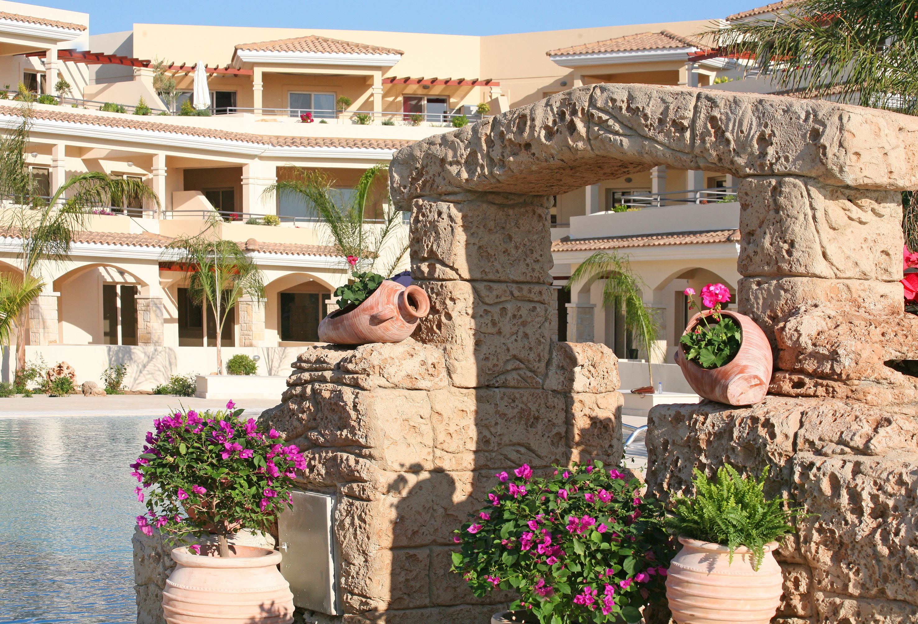 A hotel with a pool, stone pillars, and potted plants.
