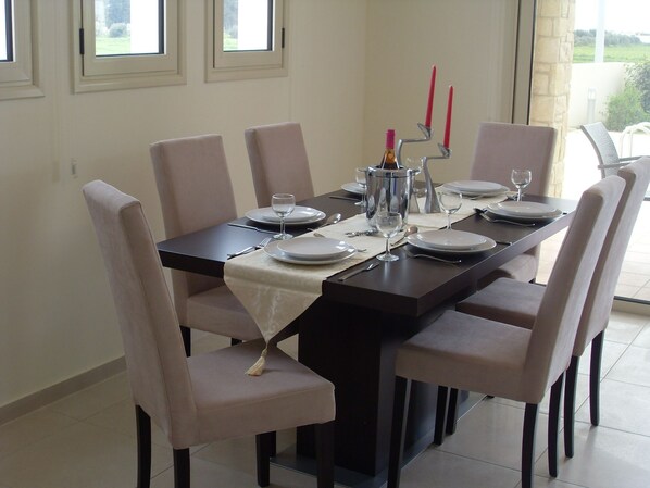 A dining table set for six with a candle holder, wine glasses, and plates.