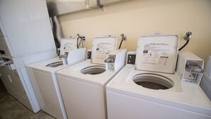Une rangée de lave-linge et de sèche-linge à chargement frontal, tous blancs, dans une buanderie.