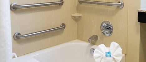 A bathroom with a walk-in shower, grab bars, a white bathtub, and a towel rack.