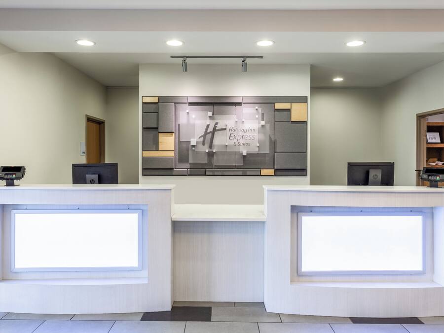 A hotel reception area with two reception desks, a wall-mounted sign, and a ceiling light fixture.