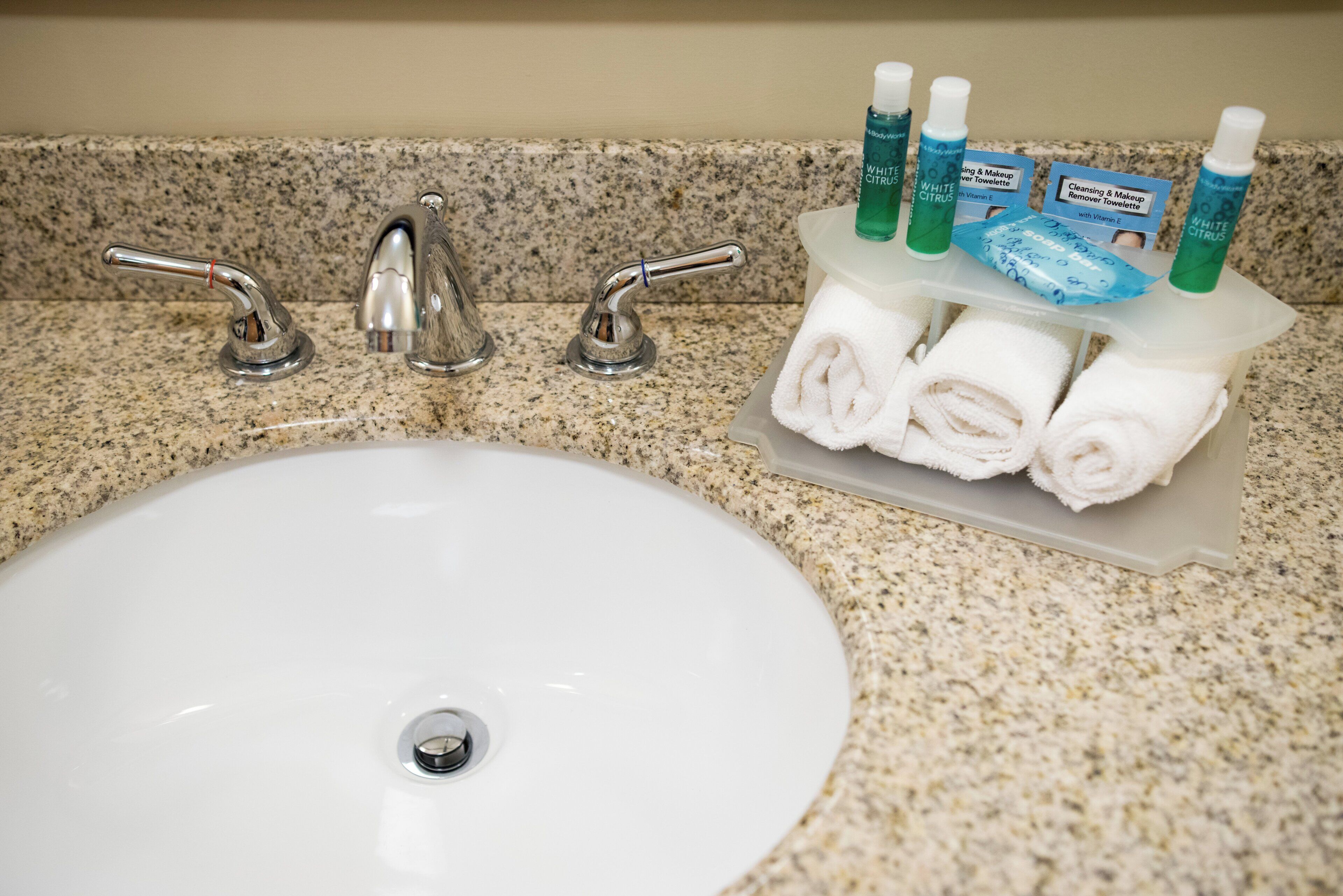 A bathroom sink with a granite countertop, a chrome faucet, and a soap dispenser.