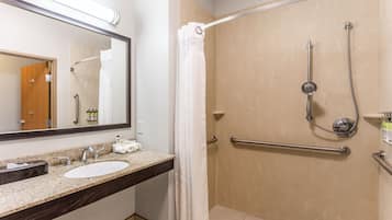 A bathroom with a sink, mirror, shower, and grab bars.