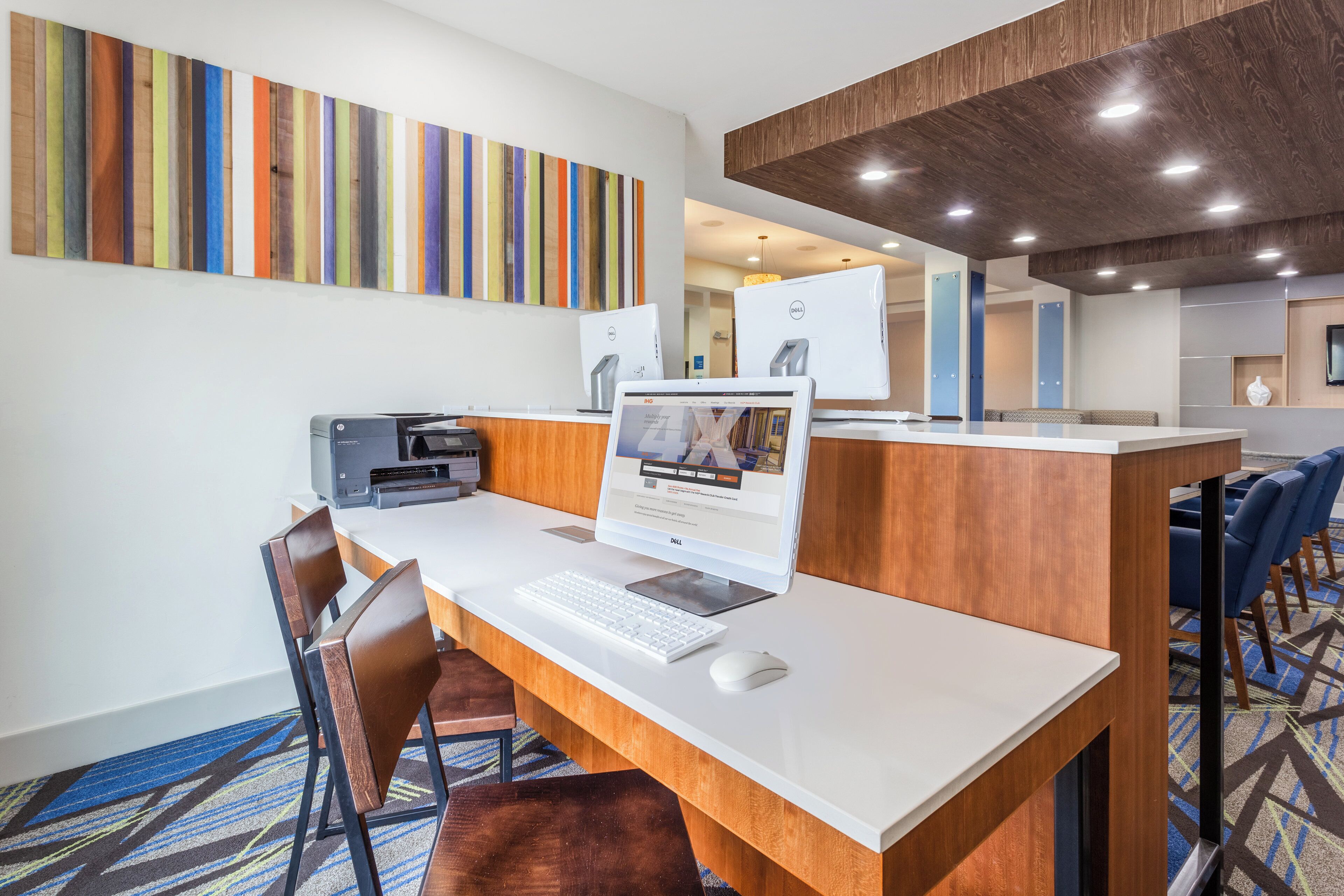 A hotel reception area with a desk, computer, printer, and seating.