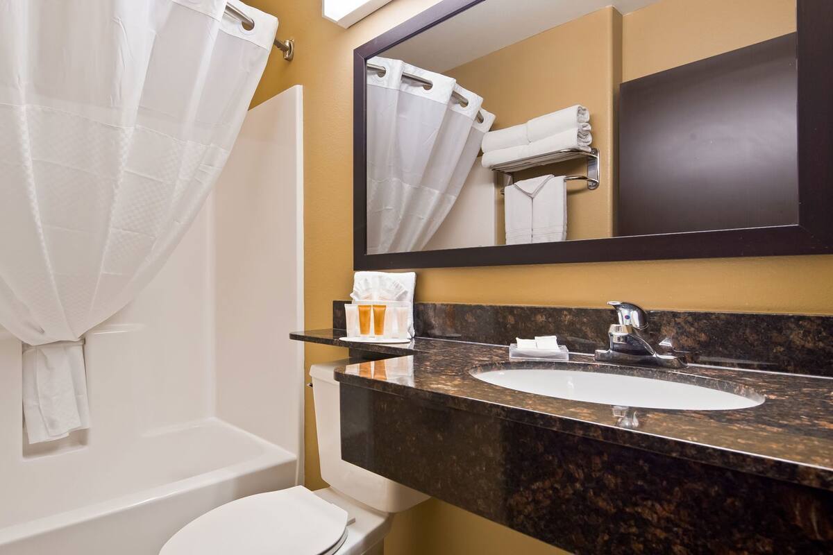 A bathroom with a bathtub, toilet, sink, and a large mirror.