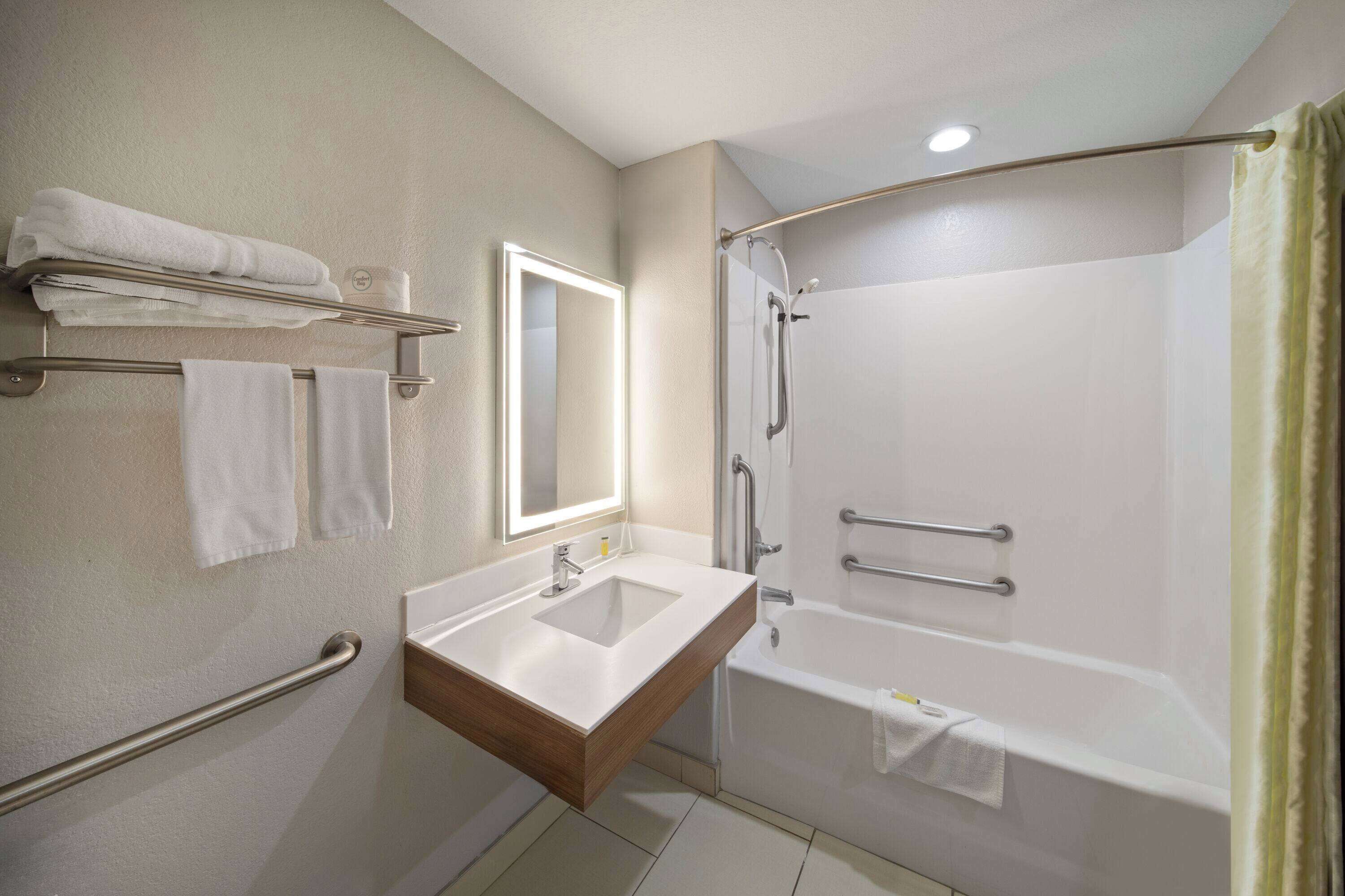 Un baño moderno con lavabo, espejo y ducha.