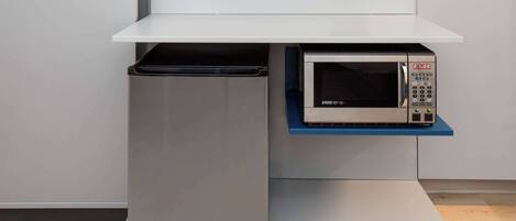 A kitchen with a microwave and a built-in oven on a white countertop.