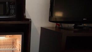 A room with a microwave, a television, and a refrigerator.