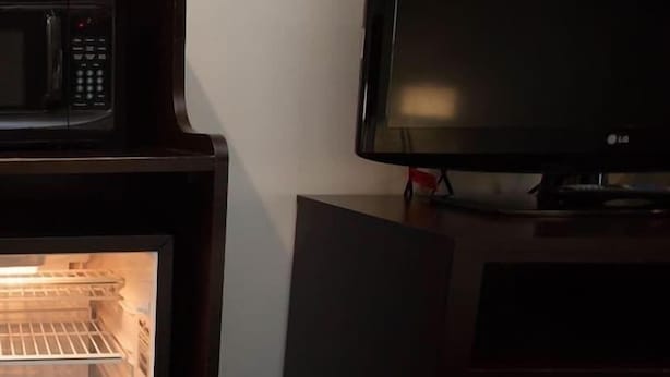Una habitación con microondas, televisión y refrigerador.