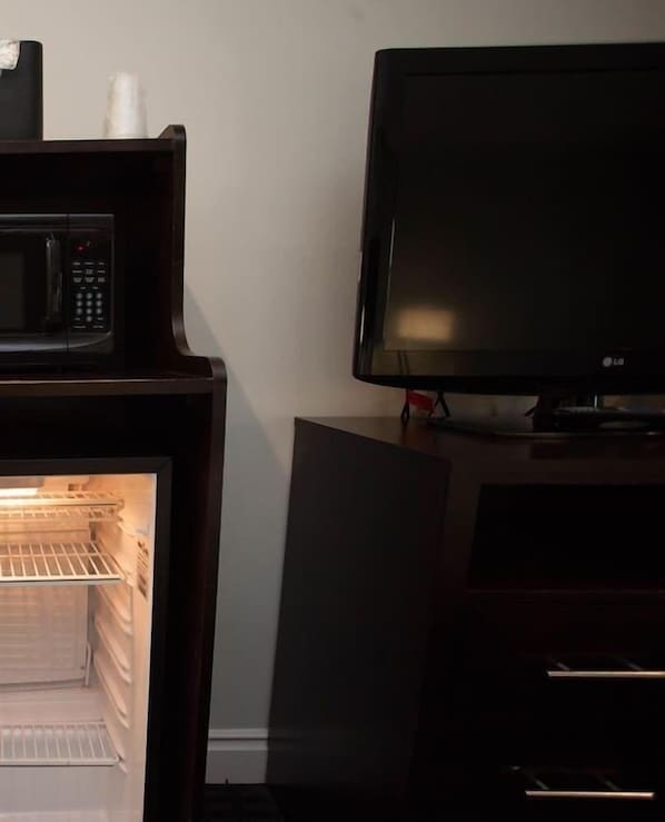 A room with a microwave, a television, and a refrigerator.