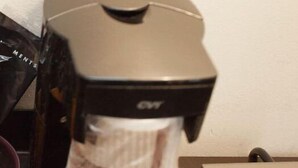 A coffee machine with a black top and a transparent water reservoir.