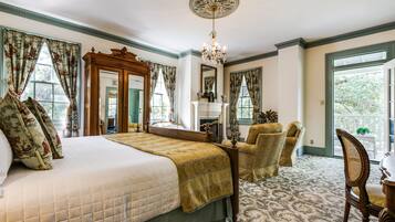 A spacious bedroom with a large bed, a wooden dresser, a mirror, and a chandelier.