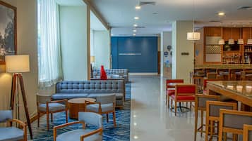 A hotel lobby with seating areas, a bar, and a reception desk.