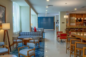 Un hall de hotel con zonas de estar, un bar y una recepción.