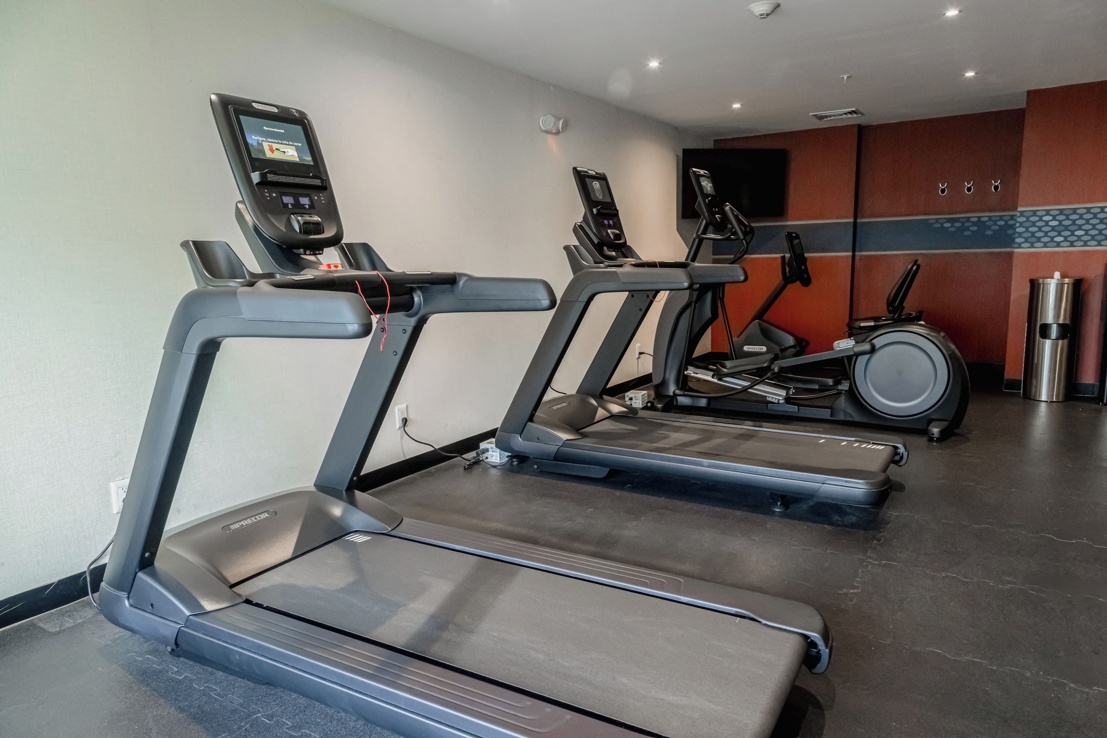 A gym with treadmills, an elliptical, and a stationary bike.