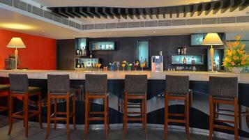 A bar area with a modern design, featuring a curved counter and multiple bar stools.