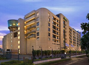 Un hôtel moderne à plusieurs étages, doté de balcons et agrémenté d’une fontaine centrale.