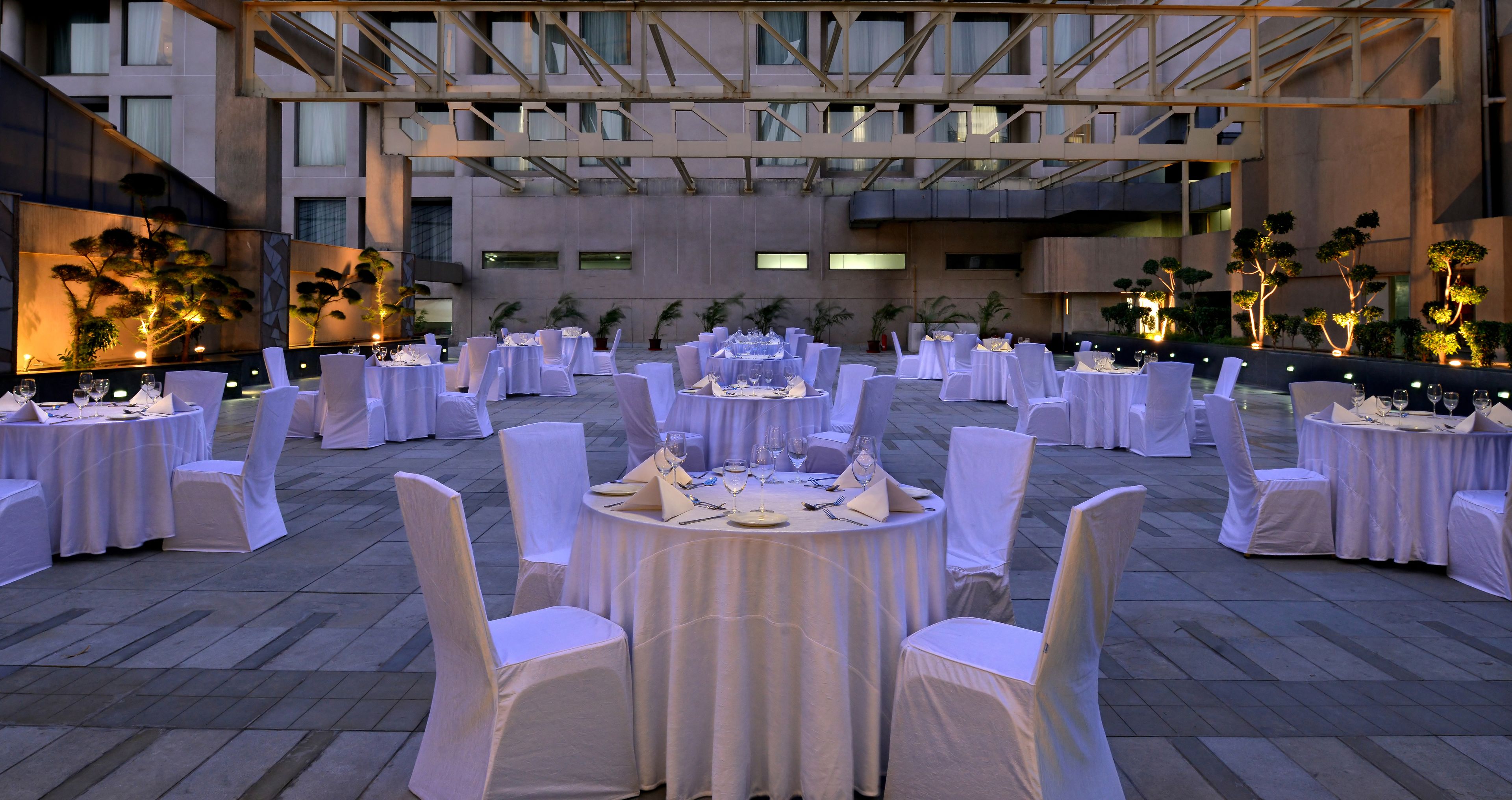 Een ruim buitendinergedeelte met ronde tafels en witte stoelen, ingericht voor een formeel evenement.
