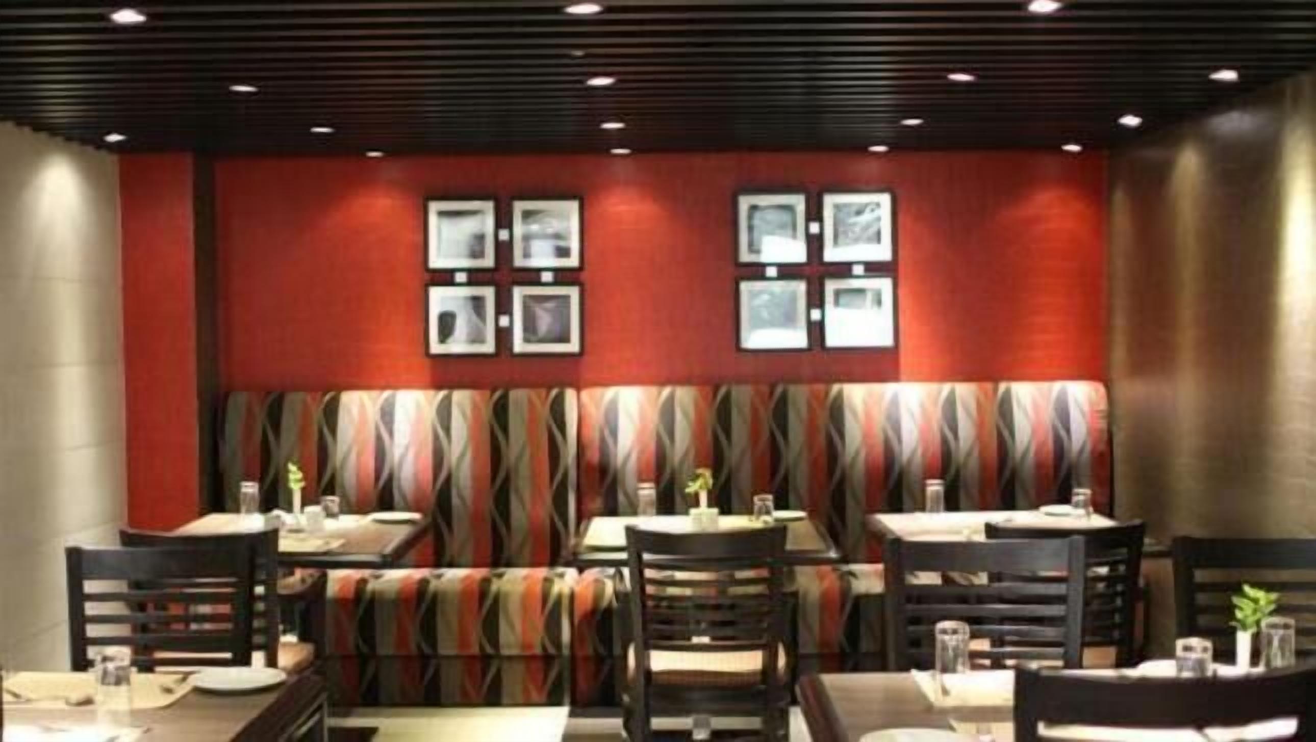 Ein Restaurant mit Sitzecken und Tischen, roten Wänden und gerahmten Bildern.