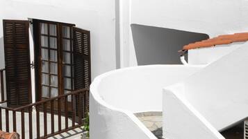 A white building with a curved staircase and wooden shutters.