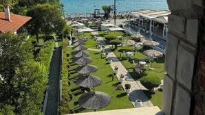 Vista para o mar a partir de uma varanda com vista para uma área de restaurantes e mesas ao ar livre, com guarda-sóis.