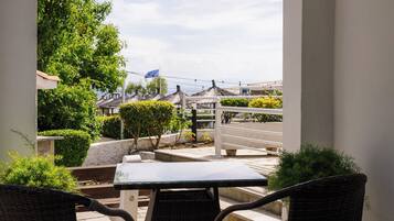 Un patio al aire libre con mesa y sillas, vista a la calle y edificios, y un cielo despejado.